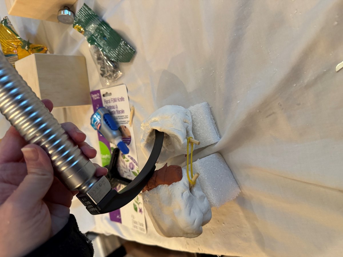 First prototype of the Bairway Trainer, made from clay, foam, and rubber bands with a laryngoscope blade inserted.