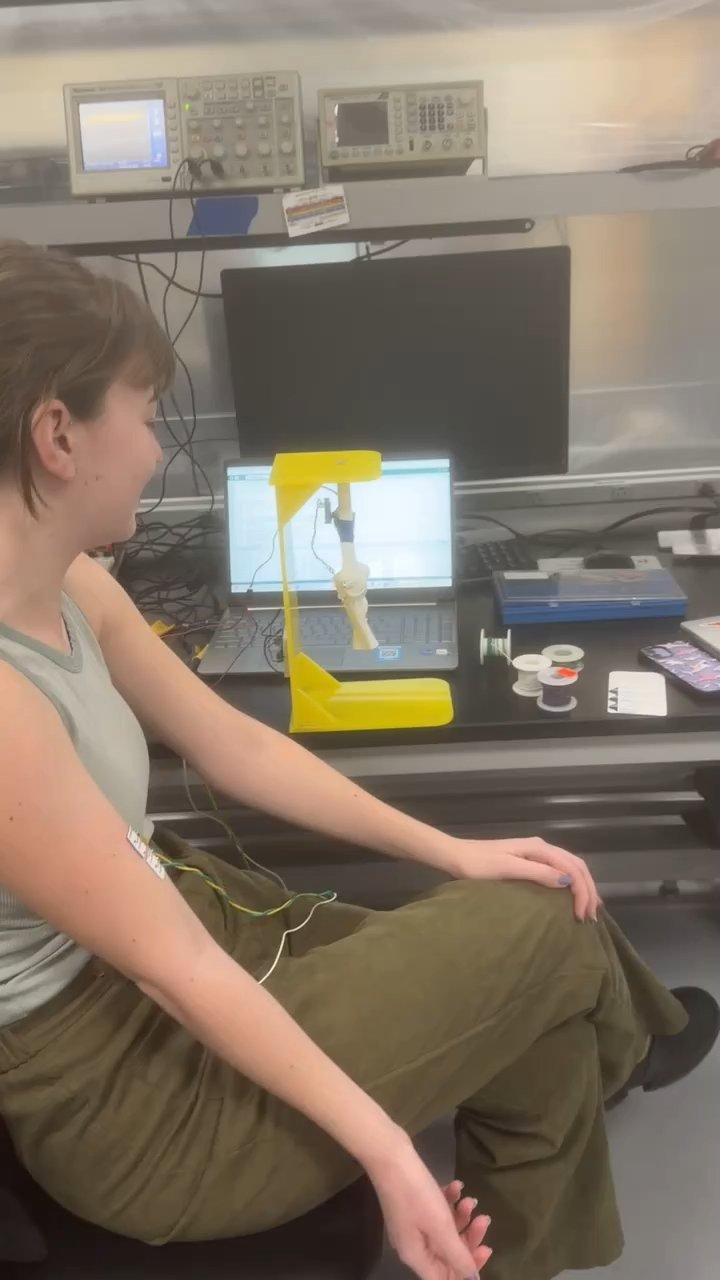 A test user wearing the EMG-activated elbow brace prototype in the lab, with electrodes visible on the forearm.