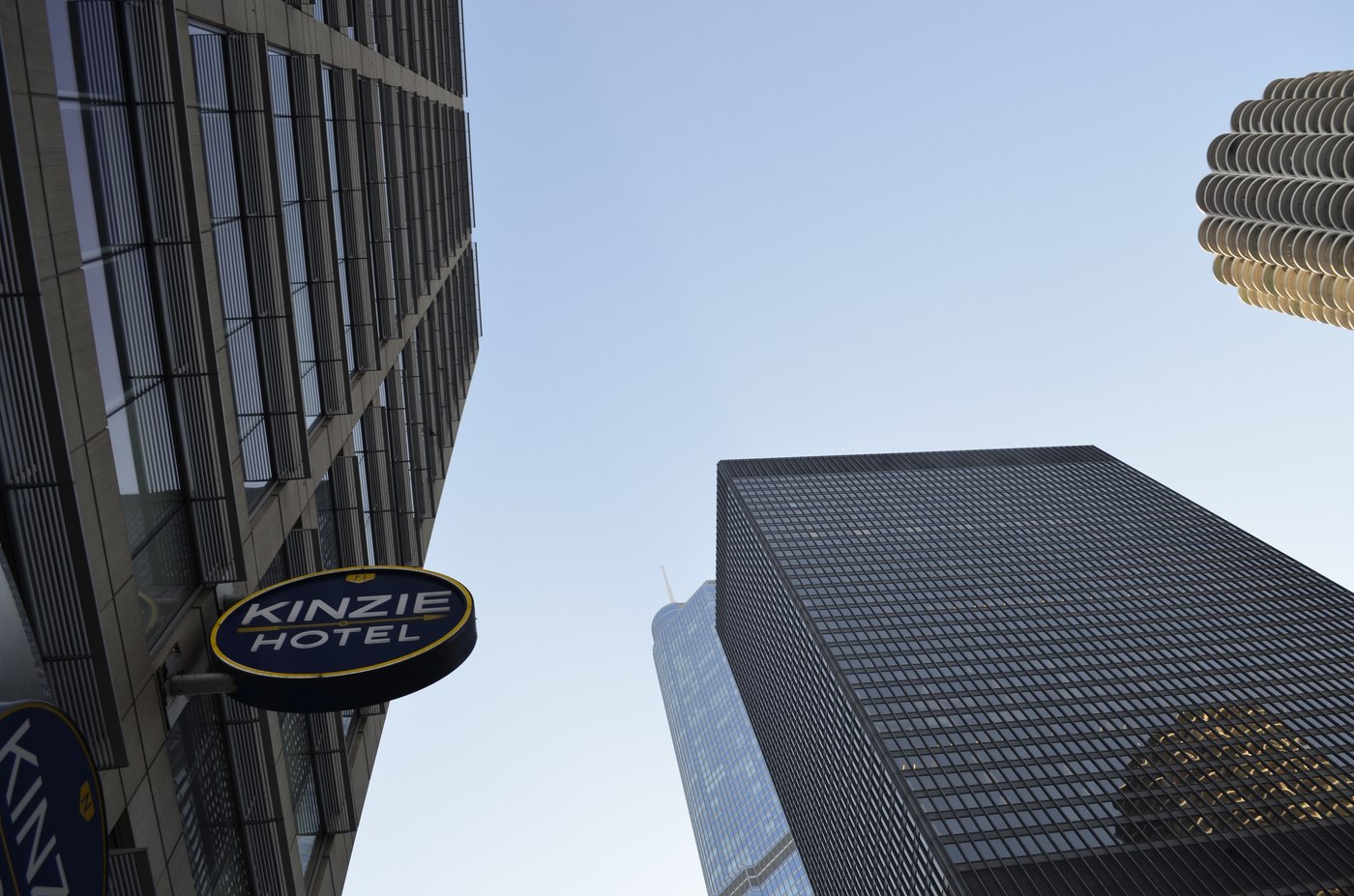 Looking up at the Kinzie Hotel sign between two Chicago skyscrapers