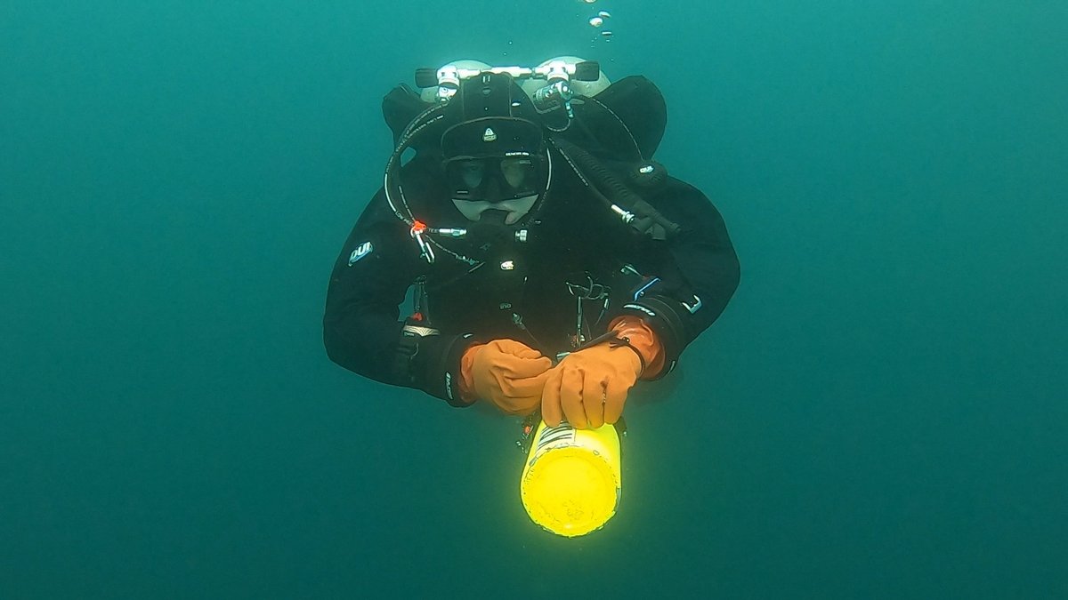 Kian scuba diving, holding a yellow stage bottle