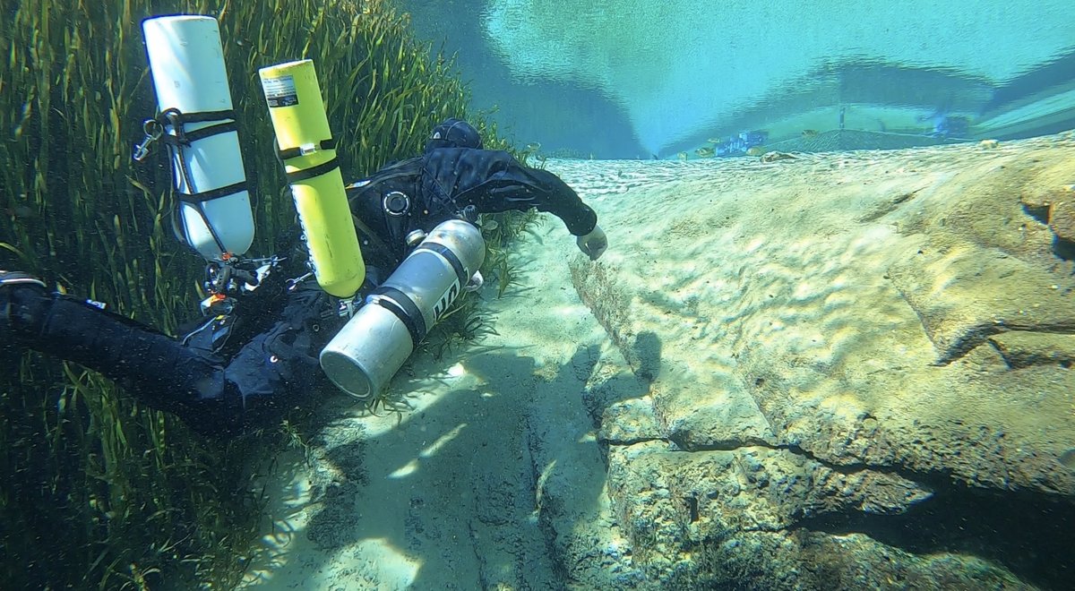 Kian scuba diving near a rock ledge