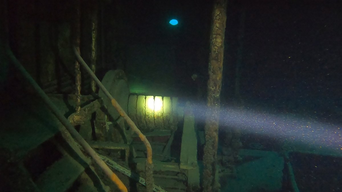 A wreck's interior showing stairs and grating, lit by a dive light