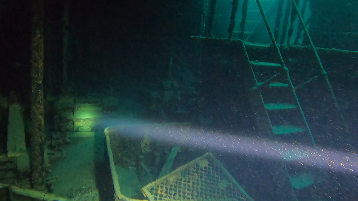 A wreck's interior with stairs and metal grating