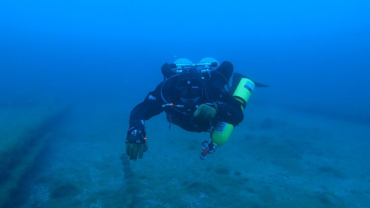 A diver with a green oxygen stage bottle facing the camera